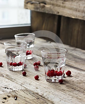 Homemade cranberry vodka, wooden background