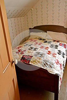 A homemade crazy quilt covers a bed in an old country upstairs bedroom.