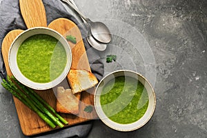 Homemade cream asparagus soup with toast on a gray background. Overhead view, copy space