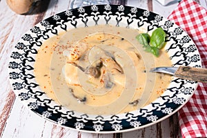 Homemade cream of chicken and mushroom soup or French style chicken fricassee, in a soup bowl on a wooden table. High view