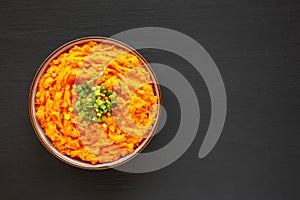 Homemade Creamy Mashed Sweet Potatoes with MIlk and Butter in a Bowl on a black background, top view. Space for text