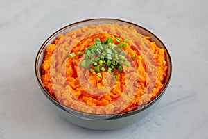 Homemade Creamy Mashed Sweet Potatoes with MIlk and Butter in a Bowl on a gray background, side view