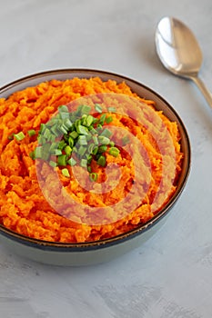 Homemade Creamy Mashed Sweet Potatoes with MIlk and Butter in a Bowl on a gray background, side view. Close-up