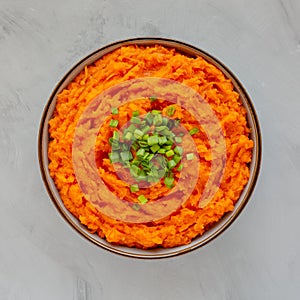 Homemade Creamy Mashed Sweet Potatoes with MIlk and Butter in a Bowl on a gray background, top view