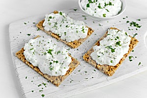 Homemade Crispbread toast with Cottage Cheese and parsley on white wooden board.