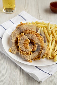 Homemade Crispy Chicken Tenders and French Fries with sauce and glass of cold beer, low angle view