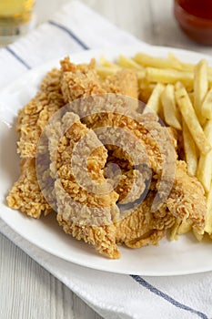 Homemade Crispy Chicken Tenders and French Fries with sauce and glass of cold beer, side view. Close-up