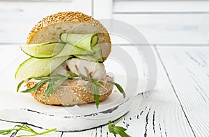 Homemade crispy spring fish burger with spicy chilli mayo on white rustic wooden board over light background. Copy space.