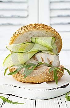 Homemade crispy spring fish burger with spicy chilli mayo on white rustic wooden board over light background. Copy space.