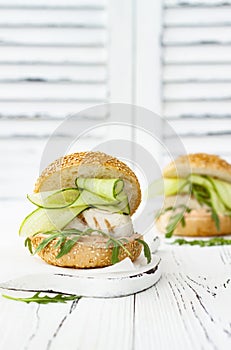 Homemade crispy spring fish burger with spicy chilli mayo on white rustic wooden board over light background. Copy space.