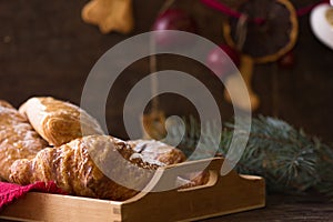 Homemade croissant and holiday decoration toys tree fir branches on white wooden table. Top view copy space. Morning New Year 2018