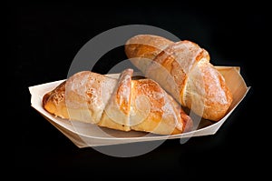 Homemade croissants in a bio wooden dish, isolated on black background