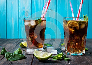 Homemade Cuba Libre with fresh lime, brown rum and crushed ice on an old wooden table