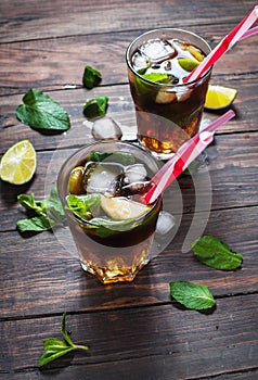 Homemade Cuba Libre with fresh lime, brown rum and crushed ice on an old wooden table