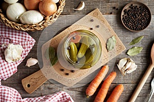 Homemade cucumber pickles or gherkins in a glass jar on a table, top view