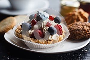 Homemade cupcake with blueberries, cream and fresh berries on wooden background