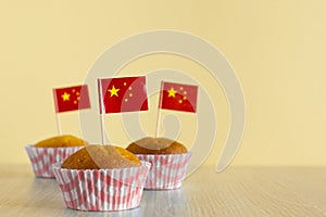 Homemade cupcake with China flag on beige wood background. Holiday Independence Day. Chinese flag decorates cakes.