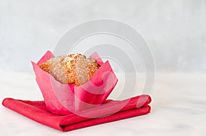 Homemade cupcake on a white plate. Festive pastries of bright spring flowers on a red safet. Close-up, side view. Copy