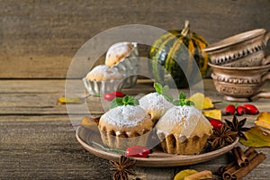 Homemade cupcakes with powdered sugar with cinnamon sticks, anise stars, pumpkins, berries of rosehip and autumn leaves