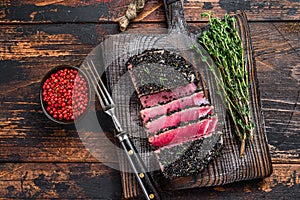 Homemade Cut Grilled Sesame Tuna steak on a cutting board. Dark Wooden background. Top view