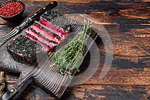 Homemade Cut Grilled Sesame Tuna steak on a cutting board. Dark Wooden background. Top view. Copy space