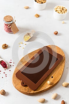 Homemade dark chocolate bar in mold with dried berries and nuts on white background. Side view. Chocolatier work