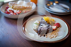 Homemade dark chocolate brownies and strawberry and fresh orrange