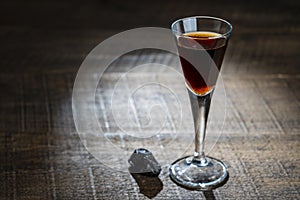 Homemade dark damson plum brandy in glasses on a wooden table, closeup. Drink from dry plums