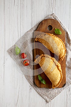 Homemade Deep Fried Italian Panzerotti Calzone on a rustic wooden board on a white wooden background, top view. Flat lay, overhead