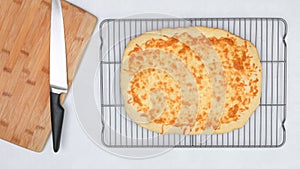 Homemade delicious flat bread with mozzarella cheese topping close up on cooling rack