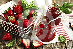 Homemade delicious strawberry jam with basil in a glass jar and