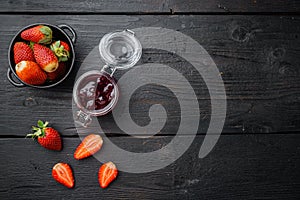 Homemade delicious strawberry jam and with fresh berries, on black wooden table background, top view flat lay with copy space for