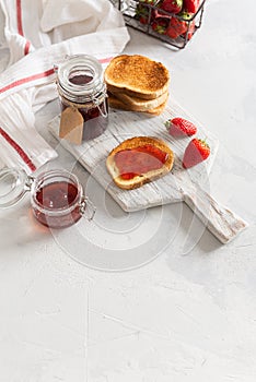 Homemade delicious strawberry jam with toasts and fresh strawberry on a rustic wooden board. Copy space for text or product.