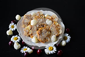 Homemade dessert of toffee and corn sticks on a white antique plate with a gold rim, decorated with corn sticks, cherries and