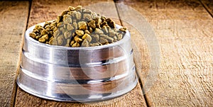 Homemade dog food in metallic bowl on wooden background, copy space