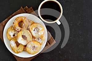 Homemade donuts on white plate, cup of black coffee