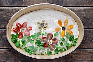 Homemade dough for delicious, italian focaccia in round baking bowl. Decoration is made of cherry tomatoes, olives and fresh herbs