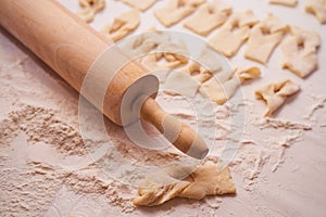 Homemade dough with a rolling pin on a light background of flour