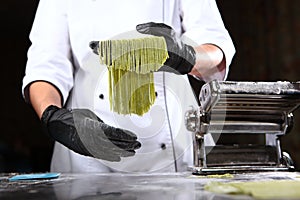 Homemade dough with spinach. The chef holds in her hands a freshly cooked spaghetti from dough with the addition of spinach.Useful