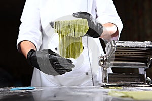 Homemade dough with spinach. The chef holds in her hands a freshly cooked spaghetti from dough with the addition of spinach.Useful