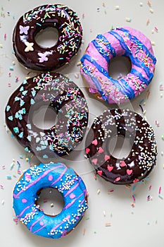 Homemade doughnuts with colored frosting and sprinkles on a gray background