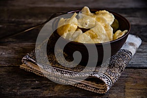 Homemade dumplings in clay pots on the kitchen table, fork and folklor napkin.