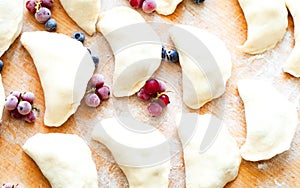 Homemade dumplings or Pierogi on wooden background with flour. Traditional Ukrainian or Polish food