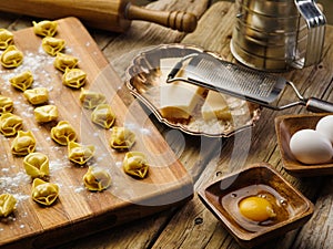 Homemade dumplings on a wooden board, ingredients, kitchen utensils on a wooden kitchen table. The process of making homemade