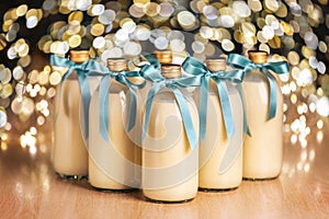 Homemade eggnog in bottles with blue bows on light spotty background