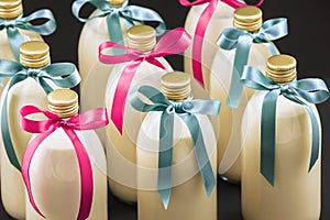 Homemade eggnog in bottles with blue and pink bows on dark background