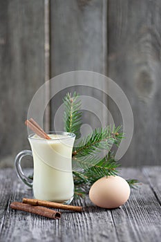 Homemade eggnog with cinnamon for Christmas and winter holidays on wooden table