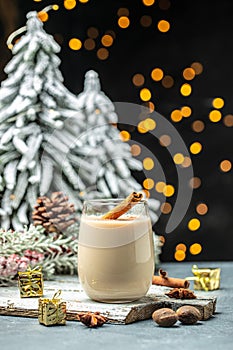 Homemade eggnog with cinnamon in glass on wooden board. Typical Christmas dessert. place for text