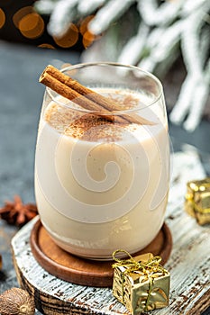Homemade eggnog with cinnamon in glass on wooden board. Typical Christmas dessert. vertical image. top view. copy space