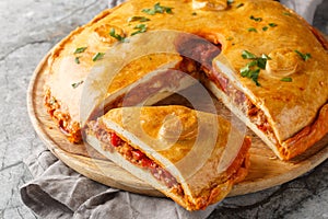 Homemade Empanada Gallega large Spanish pie filled with meat or fish and vegetables close-up on a board. Horizontal